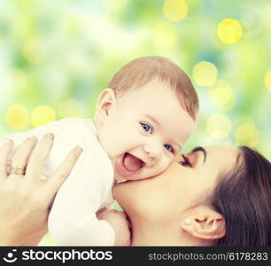 people, family, motherhood and children concept - happy mother hugging adorable baby over green lights background