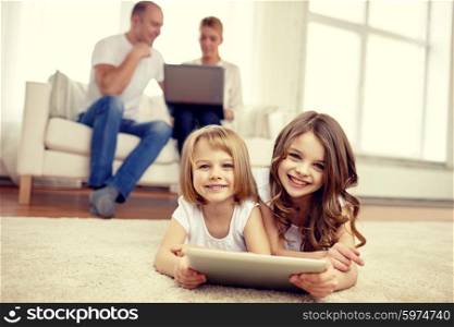 people, family, technology and children concept - happy little girls playing with tablet pc computer at home
