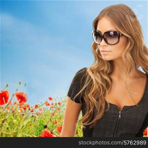 people, fashion, elegance and style concept - beautiful young woman in shades over blue sky and poppy field background