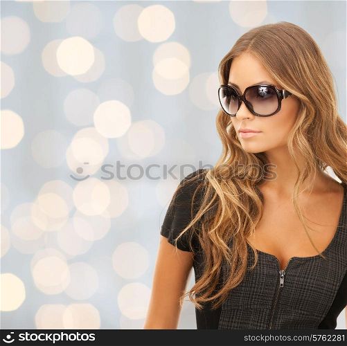 people, fashion, elegance and style concept - beautiful young woman in shades over holidays lights background