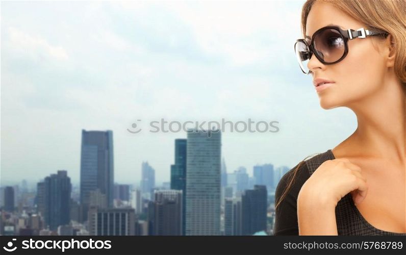 people, fashion, eyewear and style concept - beautiful woman in shades over city background