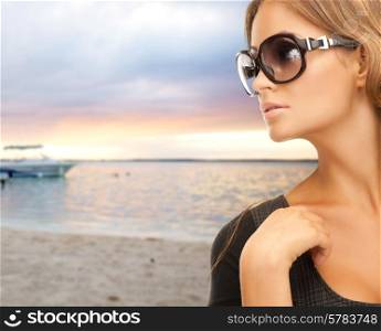 people, fashion, eyewear, travel and concept - beautiful woman in shades over sea with boat and sky background