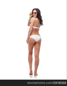people, fashion, swimwear, summer and beach concept - happy young woman in sunglasses and white swimsuit looking back
