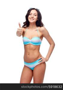 people, fashion, swimwear, summer and beach concept - happy young woman in bikini swimsuit showing thumbs up gesture