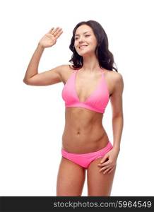 people, fashion, swimwear, summer and beach concept - happy young woman in pink bikini swimsuit waving hand