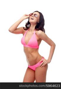 people, fashion, swimwear, summer and beach concept - happy young woman in sunglasses and pink swimsuit looking up and laughing