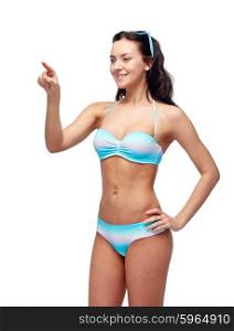 people, fashion, swimwear, summer and beach concept - happy young woman in bikini swimsuit pointing finger to something imaginary