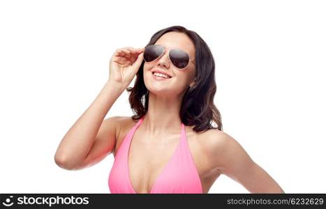 people, fashion, swimwear, summer and beach concept - happy young woman in sunglasses and pink bikini swimsuit