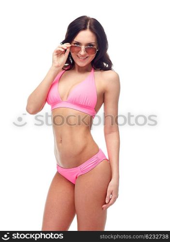 people, fashion, swimwear, summer and beach concept - happy young woman in sunglasses and pink swimsuit looking at you