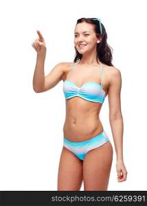 people, fashion, swimwear, summer and beach concept - happy young woman in bikini swimsuit pointing finger to something imaginary