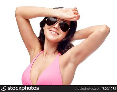 people, fashion, swimwear, summer and beach concept - happy young woman in sunglasses and pink swimsuit