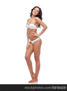 people, fashion, swimwear, summer and beach concept - happy young woman in white bikini swimsuit