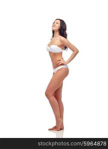 people, fashion, swimwear, summer and beach concept - happy young woman in white bikini swimsuit