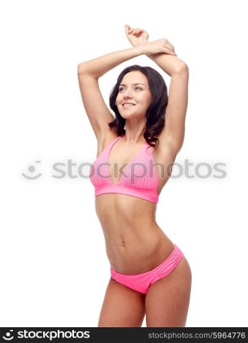 people, fashion, swimwear, summer and beach concept - happy young woman posing in pink bikini swimsuit with raised hands looking up