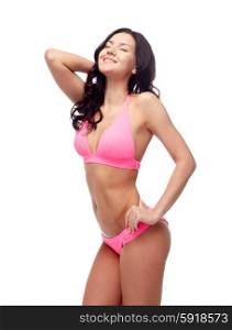 people, fashion, swimwear, summer and beach concept - happy young woman posing in pink bikini swimsuit