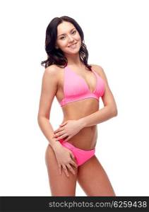 people, fashion, swimwear, summer and beach concept - happy young woman posing in pink bikini swimsuit