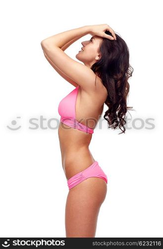 people, fashion, swimwear, summer beach and beauty concept - happy young woman posing in pink bikini swimsuit