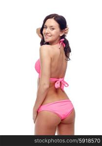 people, fashion, swimwear, summer beach and sexual concept - happy young woman in pink bikini swimsuit looking back