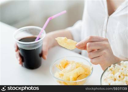 people, fast food, junk-food and unhealthy eating concept - close up of woman with popcorn, nachos or corn crisps and peanuts in bowls