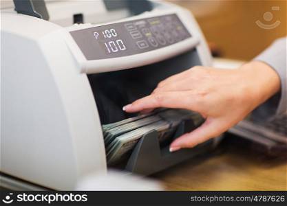 people, finance and cash concept - clerk hand counting dollars with electronic money counter machine at bank office or currency exchanger