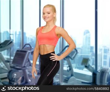 people, fitness and sport concept - happy woman fitness instructor over gym machines background