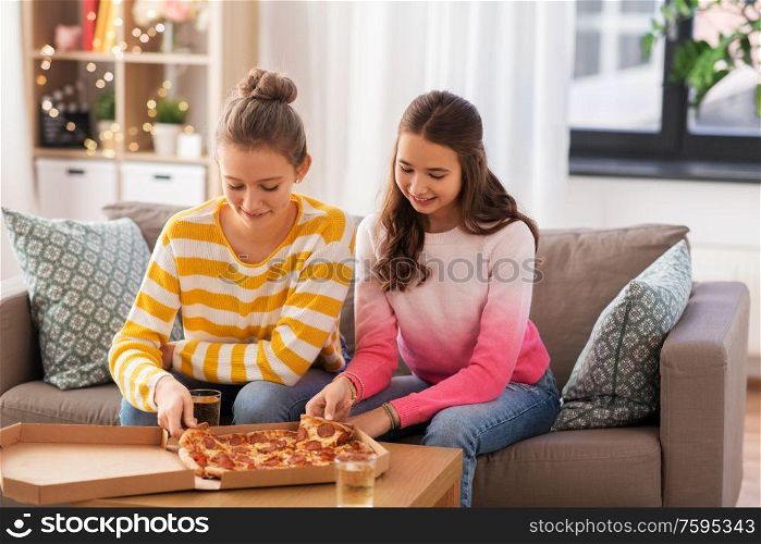 people, food and friendship concept - happy teenage girls eating takeaway pizza at home. happy teenage girls eating takeaway pizza at home