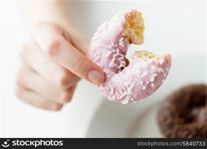 people, food, junk-food and eating concept - close up of female hand holding bitten glazed donut