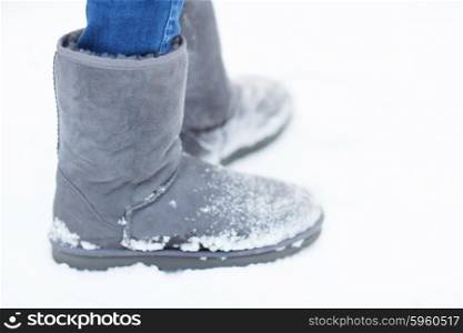 people, footwear, winter and clothing concept - close up of woman legs wearing warm boots on snow