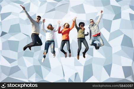 people, freedom, happiness and teenage concept - group of happy friends in sunglasses jumping high over gray low poly background
