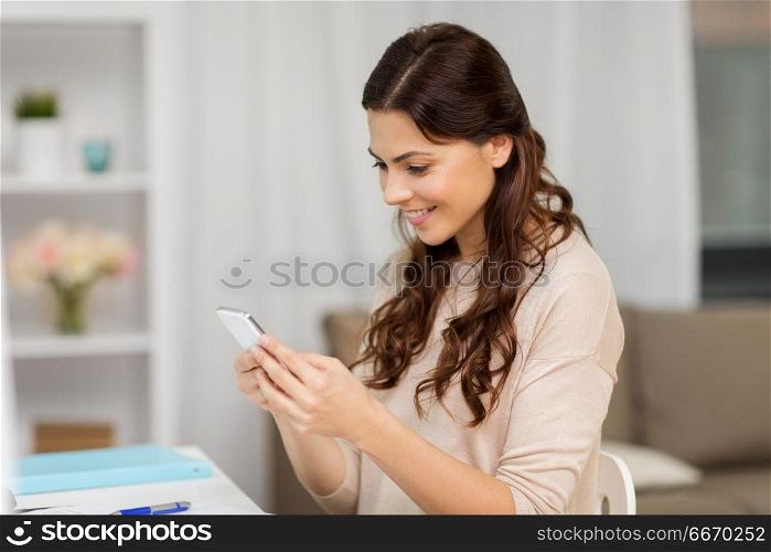 people, freelance and education concept - happy smiling woman messaging on smartphone at home. happy woman messaging on smartphone at home. happy woman messaging on smartphone at home