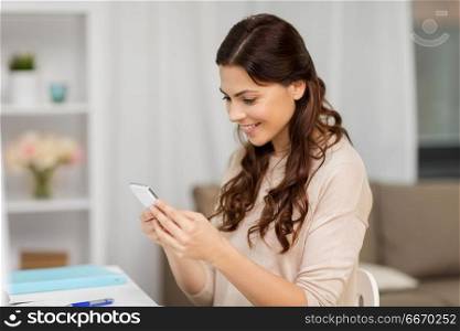 people, freelance and education concept - happy smiling woman messaging on smartphone at home. happy woman messaging on smartphone at home. happy woman messaging on smartphone at home