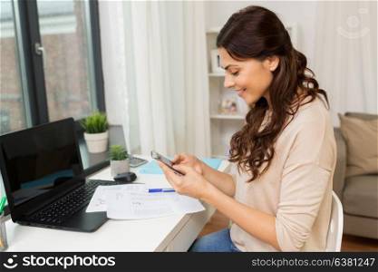 people, freelance and education concept - happy smiling woman with papers and smartphone working at home. woman with papers and smartphone working at home