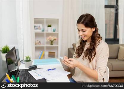 people, freelance and education concept - happy smiling woman with papers and smartphone working at home. woman with papers and smartphone working at home. woman with papers and smartphone working at home