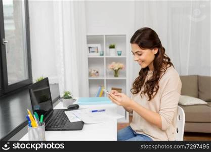 people, freelance and education concept - happy smiling woman with papers and smartphone working at home. woman with papers and smartphone working at home