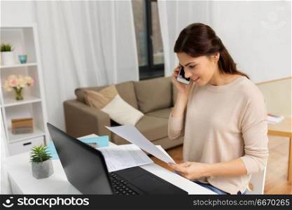 people, freelance and education concept - happy smiling woman working with papers and calling on smartphone at home. woman with papers calling on smartphone at home. woman with papers calling on smartphone at home