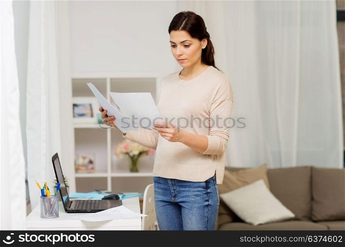 people, freelance and education concept - woman with papers and laptop working or learning at home. woman with papers working or learning at home