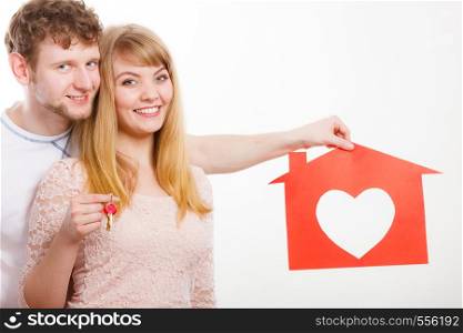 People, fresh start, real estate and love concept. Young enjoyable enamoured marriage holding red house with big heart and keys to their future.. Enamoured young marriage with house and keys.