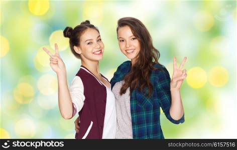 people, friends, gesture, summer and friendship concept - happy smiling pretty teenage girls hugging and showing peace hand sign over green holidays lights background