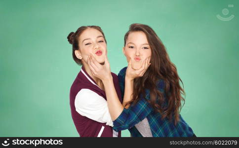 people, friends, teens and education concept - happy smiling pretty teenage girls having fun and making faces over green school chalk board background