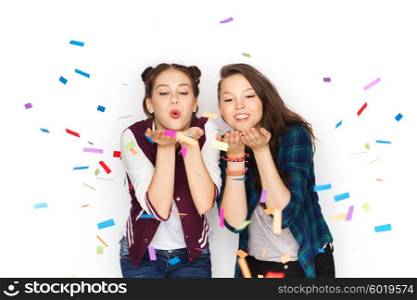 people, friends, teens and friendship concept - happy smiling pretty teenage girls having fun and blowing on confetti