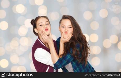 people, friends, teens and friendship concept - happy smiling pretty teenage girls having fun and making faces over holidays lights background