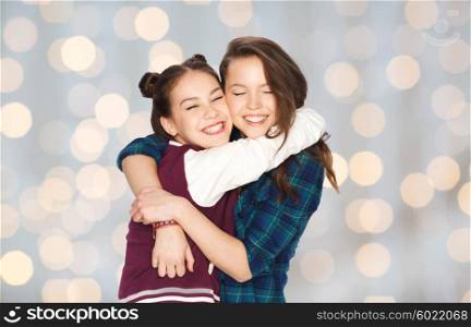 people, friends, teens and friendship concept - happy smiling pretty teenage girls hugging over holidays lights background
