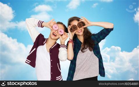 people, friends, teens and friendship concept - happy smiling pretty teenage girls with donuts making faces and having fun over blue sky and clouds background