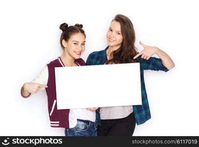 people, friends, teens and friendship concept - happy smiling pretty teenage girls holding and pointing finger to white blank board