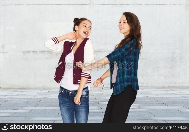 people, friends, teens and friendship concept - happy smiling pretty teenage girls dancing over gray urban street background