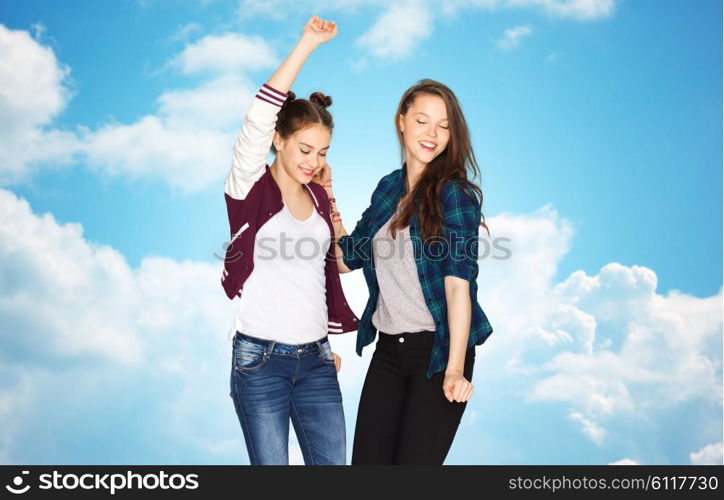 people, friends, teens and friendship concept - happy smiling pretty teenage girls dancing over blue sky and clouds background