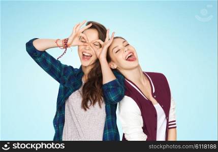 people, friends, teens and friendship concept - happy smiling pretty teenage girls having fun and making faces over blue background