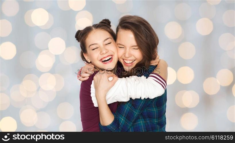 people, friends, teens and friendship concept - happy smiling pretty teenage girls hugging and laughing over holidays lights background