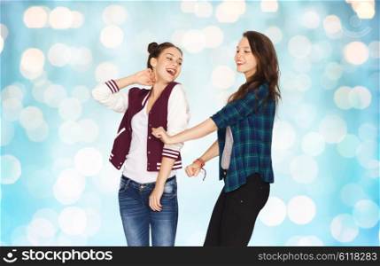 people, friends, teens and friendship concept - happy smiling pretty teenage girls dancing over blue holidays lights background