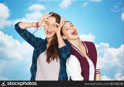 people, friends, teens and friendship concept - happy smiling pretty teenage girls having fun and making faces over blue sky and clouds background